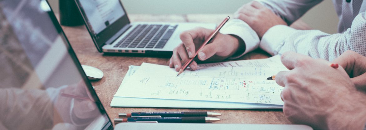 MTEL Consultants stock images of two people going over papers at a table with laptops out and pen in hand.