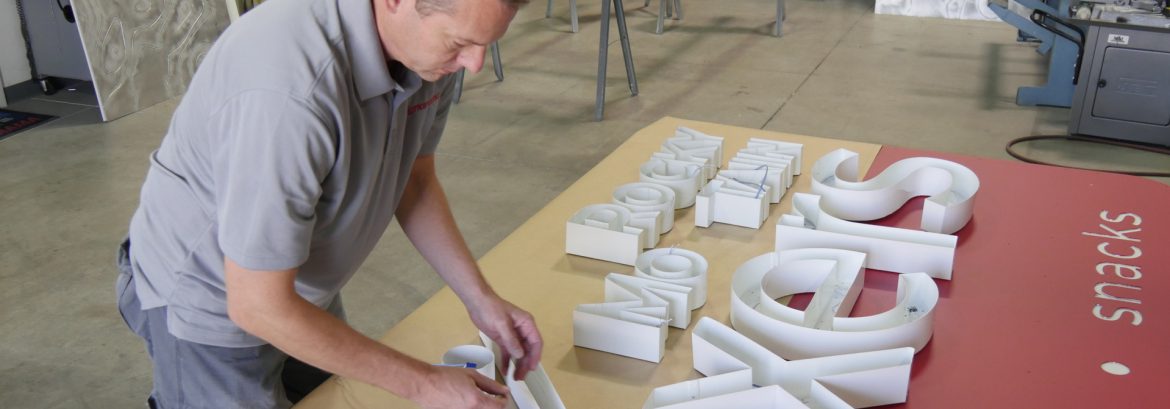 Signarama employee assembling a sign on a table.