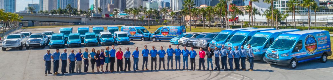 United Water Restoration Group, Inc. employees lined up in front of work vehicles for a photo.