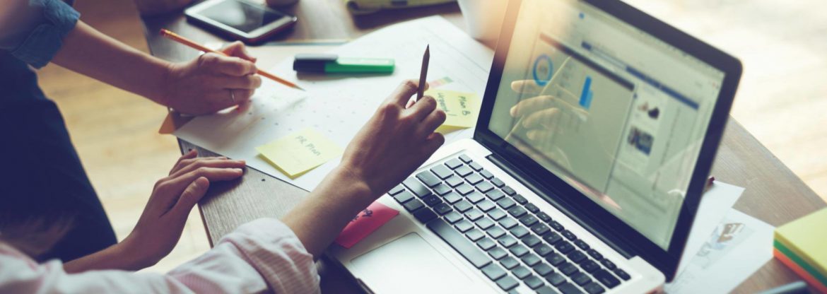 Consumer Technology Association stock photo of two people at a table with pencils, paper and a laptop.