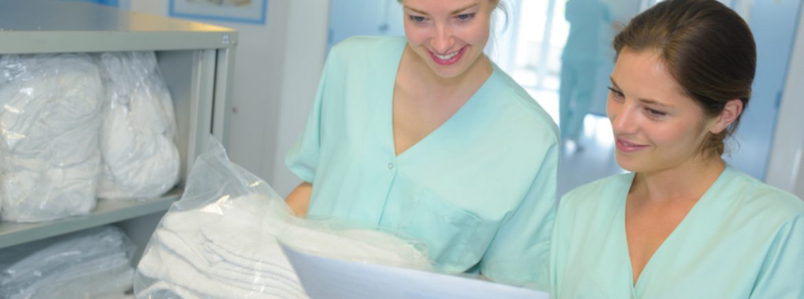 FDR Services Corp two women in healthcare related attire holding laundry items and a paper looking at it.