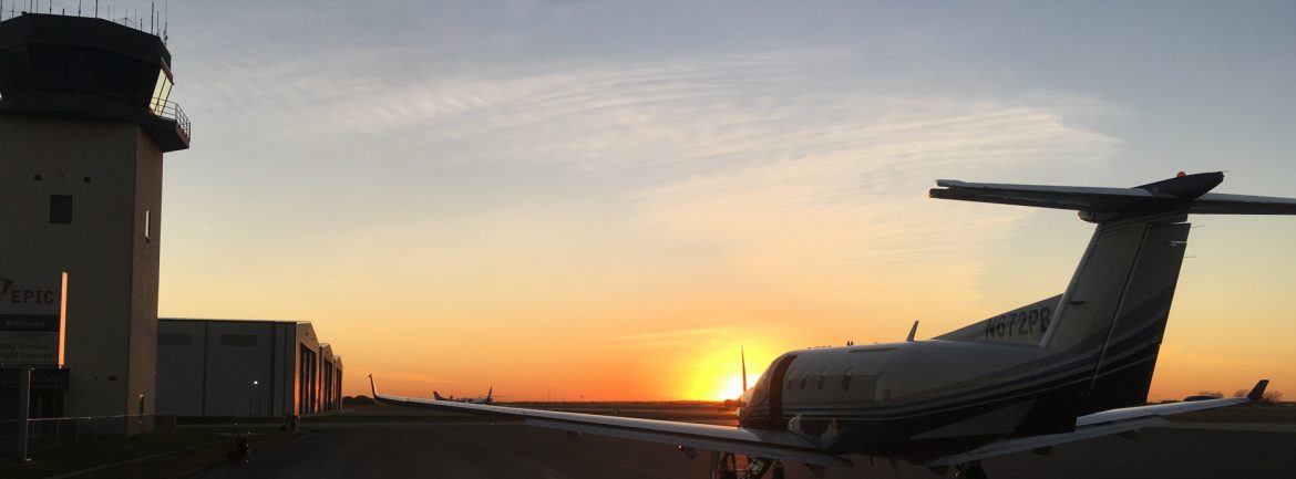 New Braunfels Regional Airport at dusk with the tower and a plane visible.