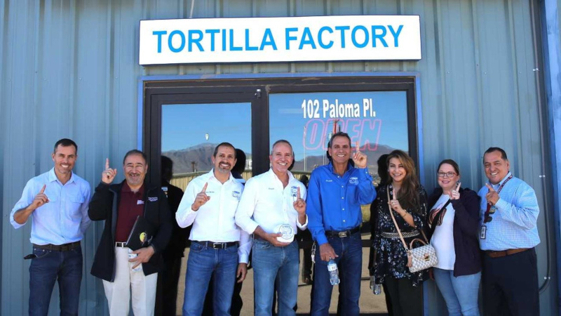 Sunland Park, New Mexico La Primera building front with employees out front for group photo holding up their hands with their index finger up.