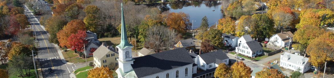 Mansfield, Massachusetts aerial with a church in the foreground and a pond beyond.